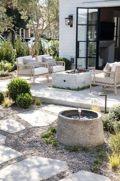 an outdoor living area with seating and fire pit in the foreground, surrounded by stone pavers