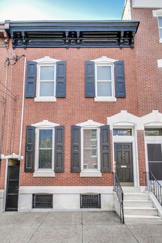 an apartment building with black shutters on the front and stairs leading up to it