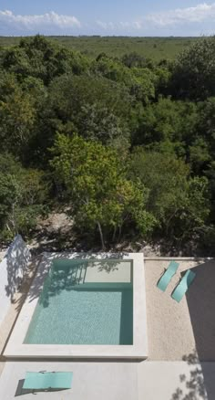 an aerial view of a pool surrounded by trees