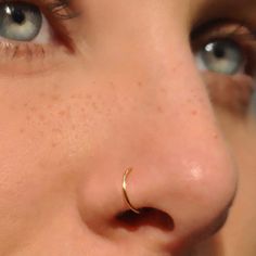 a close up of a person with a nose ring on their nose and one eye open