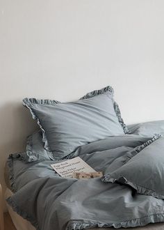 an unmade bed with blue sheets and pillows