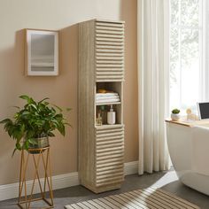 a white bath tub sitting next to a tall wooden cabinet in a room with a potted plant