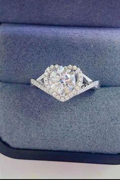 an engagement ring in a box with a cushioned surface and diamond accents on the band