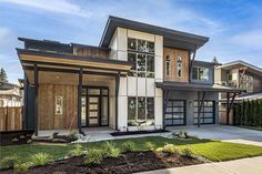 a modern house with lots of windows and wood trimmings on the front door