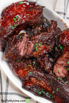 some meat is on a white plate with green sprinkles and seasoning