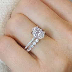 a woman's hand with a diamond ring on top of her finger and the engagement band