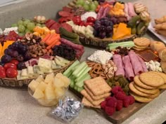 several platters of cheeses, crackers, and fruits on a counter top