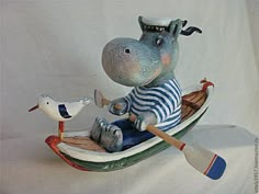 a statue of a hippopotamus rowing a boat with a bird on it