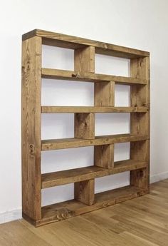 a wooden bookcase sitting on top of a hard wood floor next to a white wall