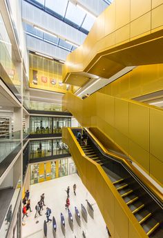 people are walking around in the atrium of a building with stairs and escalators