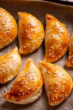 several pastries with sesame seeds are on a baking sheet