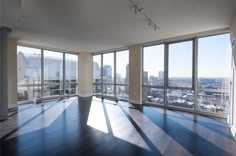 an empty living room with large windows overlooking the city