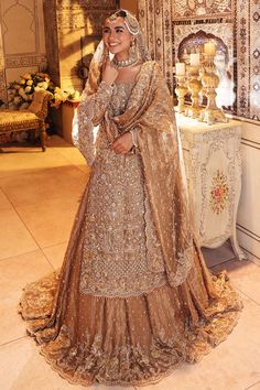 a woman in a brown and gold bridal gown standing next to a white table