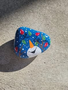 a painted rock sitting on top of a sandy ground