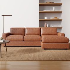 a brown leather couch sitting on top of a wooden floor next to a coffee table