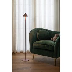 a green chair with a teddy bear sitting on it in front of a white curtain