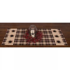 a plaid table runner with a glass jar on it and spider decorations around the edges