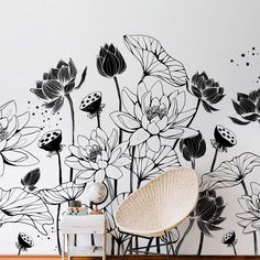 a white chair sitting in front of a wall with black and white flowers on it