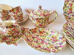 a table topped with lots of colorful plates and cups next to each other on top of a white surface