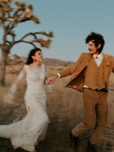 a man and woman are running through the desert holding each other's hands as they dance