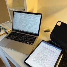 an open laptop computer sitting on top of a white desk next to a cell phone