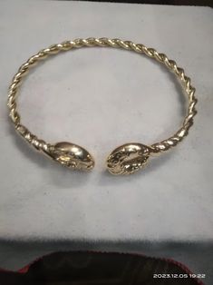 a gold bracelet with two snakes on it