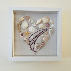 a shadow frame with sea shells and seashells arranged in the shape of a heart