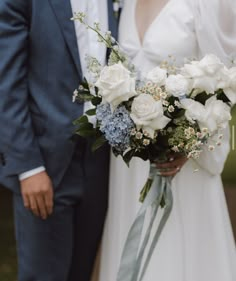 a bride and groom pose for a wedding photo with their bouquet in front of them