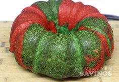 a green and red vegetable sitting on top of a wooden cutting board