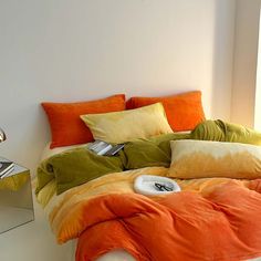 an orange and green comforter on a bed in a room with mirrored nightstands