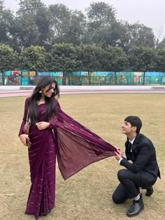 a man kneeling down next to a woman in a purple sari and black suit