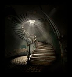 a spiral staircase in the dark with light coming from it's top and bottom