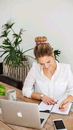 a woman sitting at a table with an open laptop computer and notebook in front of her