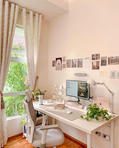 a white desk with a computer on top of it next to a window filled with pictures