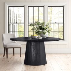 a black table with two white chairs in front of it and a potted plant on top