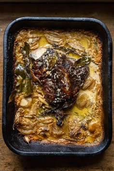 meat and vegetables in a casserole dish on a wooden table