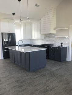 an empty kitchen with black and white cabinets, gray counter tops, and wood flooring