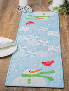 a table runner with a snowman and birds on it, sitting on a wooden floor