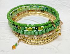 Memory wire bracelet Gold-Lined Glass Beads Sea green, grass green, light green and everything in between glass beads. Green Tiger's beads Varying shades of Tan and Cream glass beads 7/8 - 1 inch in width Naturally and comfortably adjusts to fit any size wrist Dangles add a beautiful detail Fun, Casual, Beautiful unique, eye catching piece Please contact me with any questions and requests. Thank you! Green Bohemian Stretch Bracelet With Large Beads, Adjustable Green Beaded Bracelets With Round Beads, Adjustable Green Stretch Bracelet With Large Beads, Adjustable Green Beaded Bracelet, Adjustable Green Beaded Bracelets, Green Beaded Bangle With Spacer Beads, Green Beaded Bangle Bracelets With Spacer Beads, Green Beaded Bracelets With Czech Glass, Green Beaded Czech Glass Bracelets