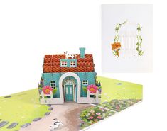 a greeting card with a house and flowers on it