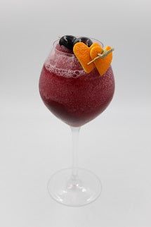 a wine glass filled with red liquid and garnished with an orange slice