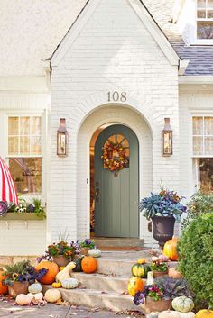 a house with pumpkins and flowers on the front steps