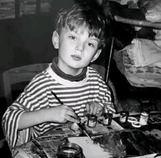 a young boy sitting at a table painting