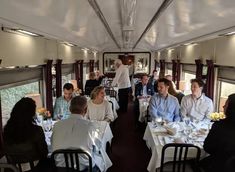 a group of people sitting at tables in a dining car on a train or boat