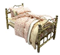 a metal bed with a pink and white comforter on it's side, against a white background