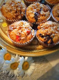 several muffins are on a plate with daisies