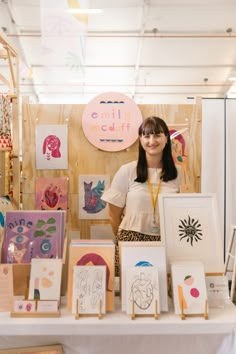 a woman standing in front of a table with art on it