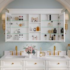 a bathroom with white cabinets and gold faucets on the sinks, along with shelves filled with personal care items