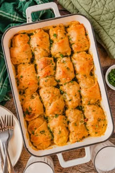 a casserole dish filled with chicken and cheese rolls, garnished with parsley