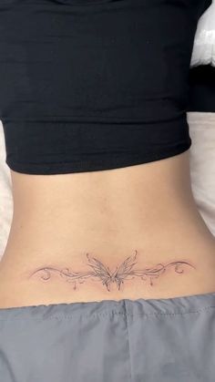 a woman's back with a butterfly tattoo on her left side ribcage